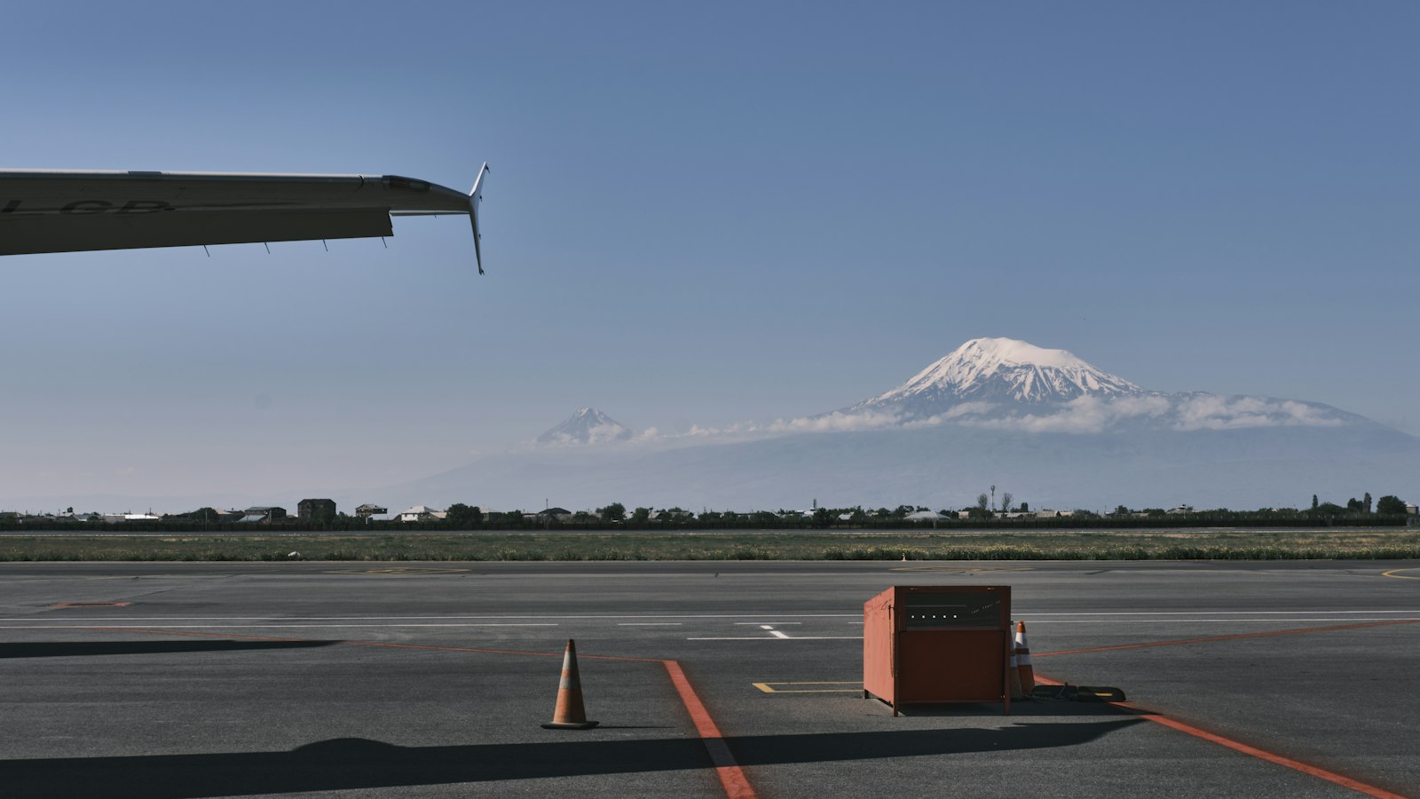 Aircraft wing over the Zvartnots airport apron, with snow-capped Mount Ararat rising beyond the runway